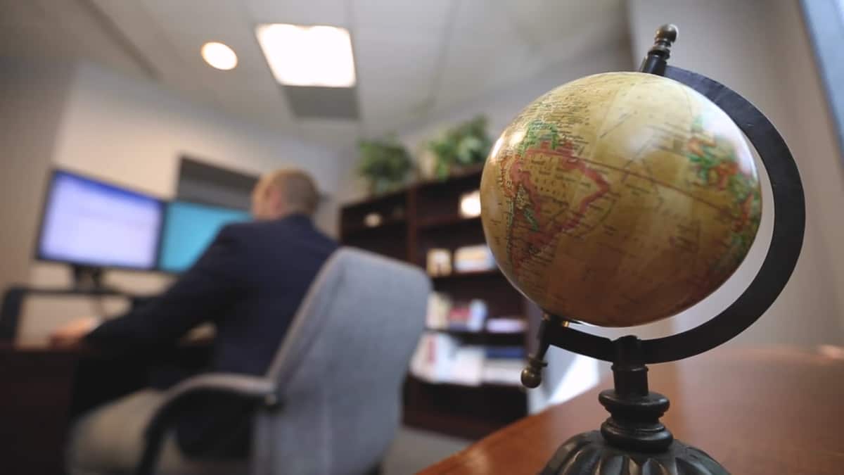 A PhilanthroCorp estate specialist working at his desk, with a globe in the foreground